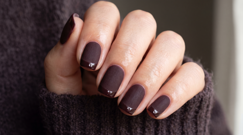 Short matte black cherry nails with glossy French tips creating a sleek texture contrast