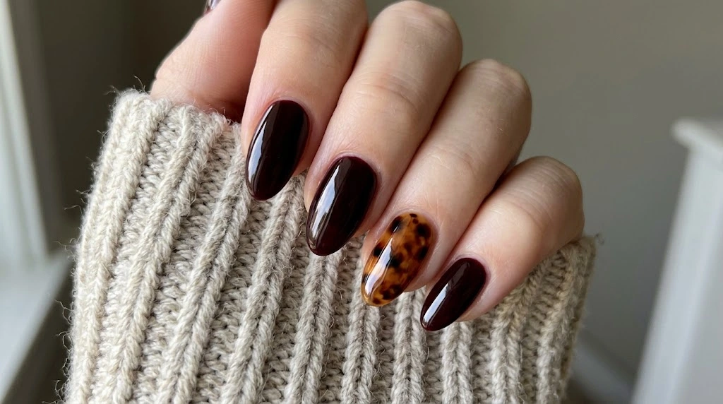Short black cherry nails paired with a glossy caramel tortoiseshell accent nail autumn design